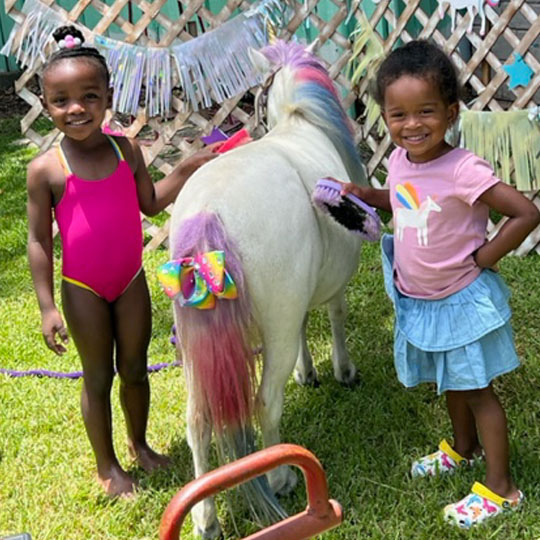 Small children playing with a pony.